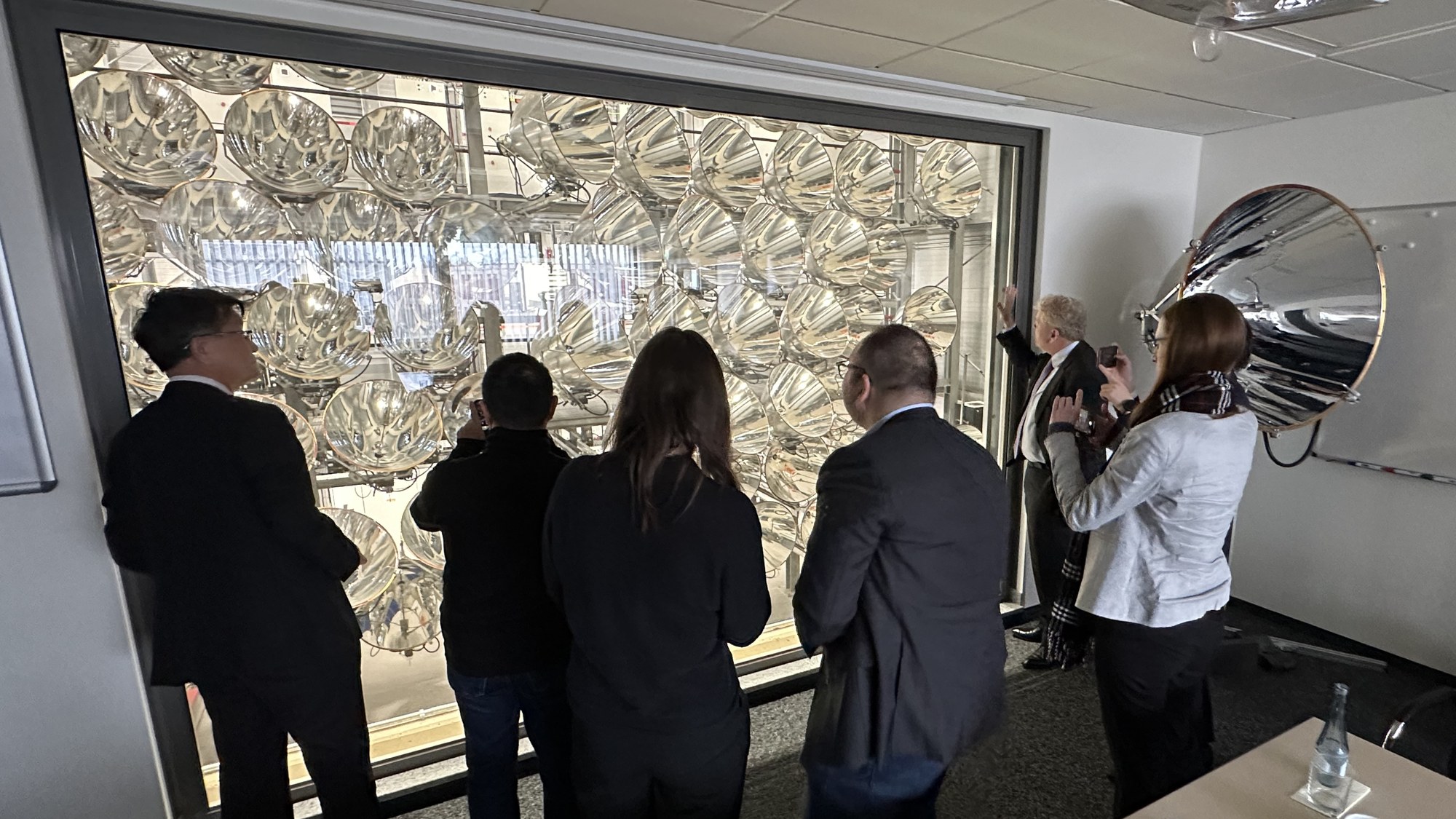 Guests of the Japanese business delegation look through a window into the Synlight's radiation hall.