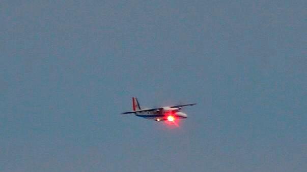 The DLR DO 228-212 research aircraft in flight with a red test laser