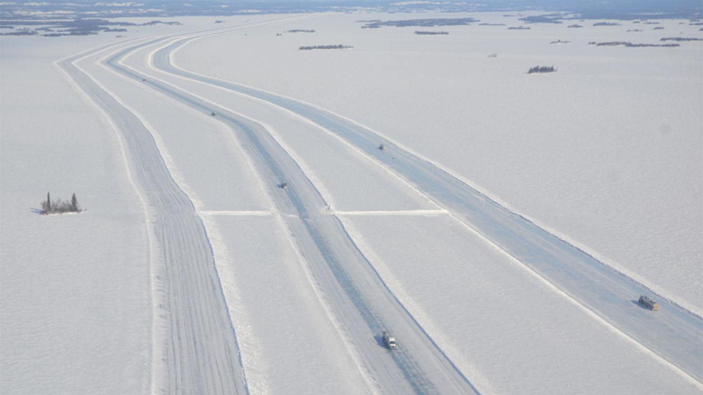 Three parallel lanes with trucks driving over the Tibbitt to Contwoyto winter road.