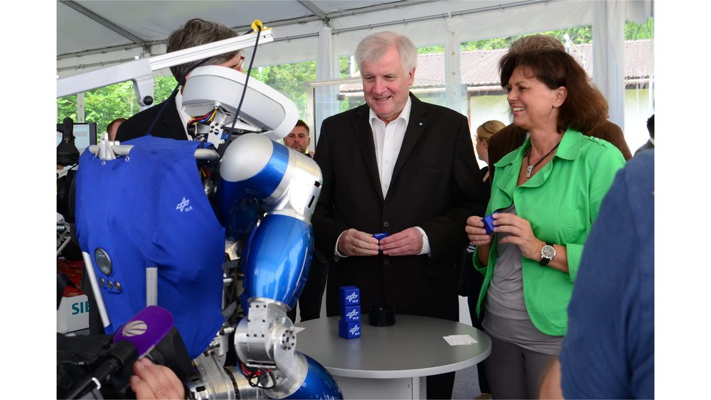 Roboter TORO steht zusammen mit Alin Albu-Schäffer, Horst Seehofer und Ilse Aigner um einen kleinen runden Tisch