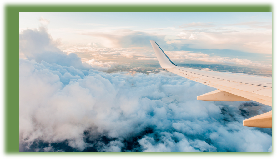 View from an airplane window over the wing and clouds