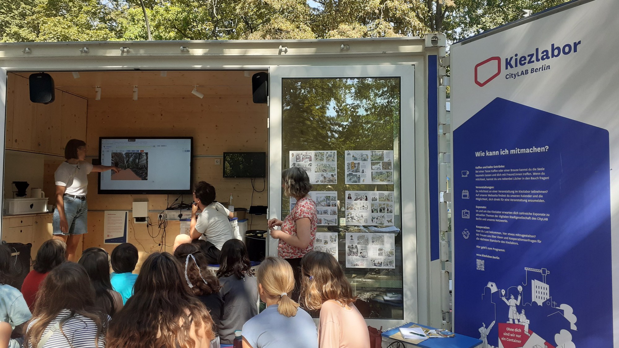 In the mobile Kiezlabor, a converted container, researchers of the project work together with the children on image generation through AI.