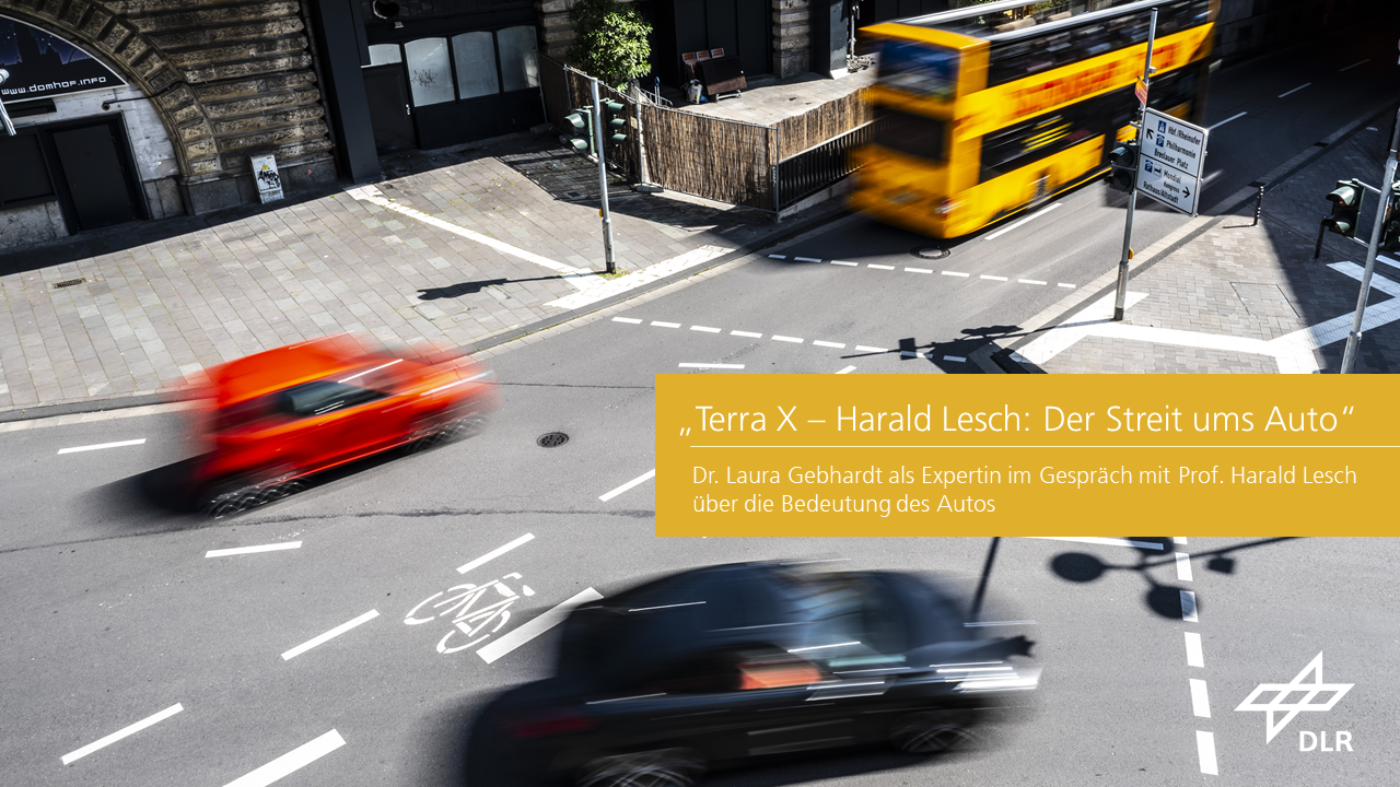 Several cars drive through a major junction. A bus is waiting at one of the traffic lights.