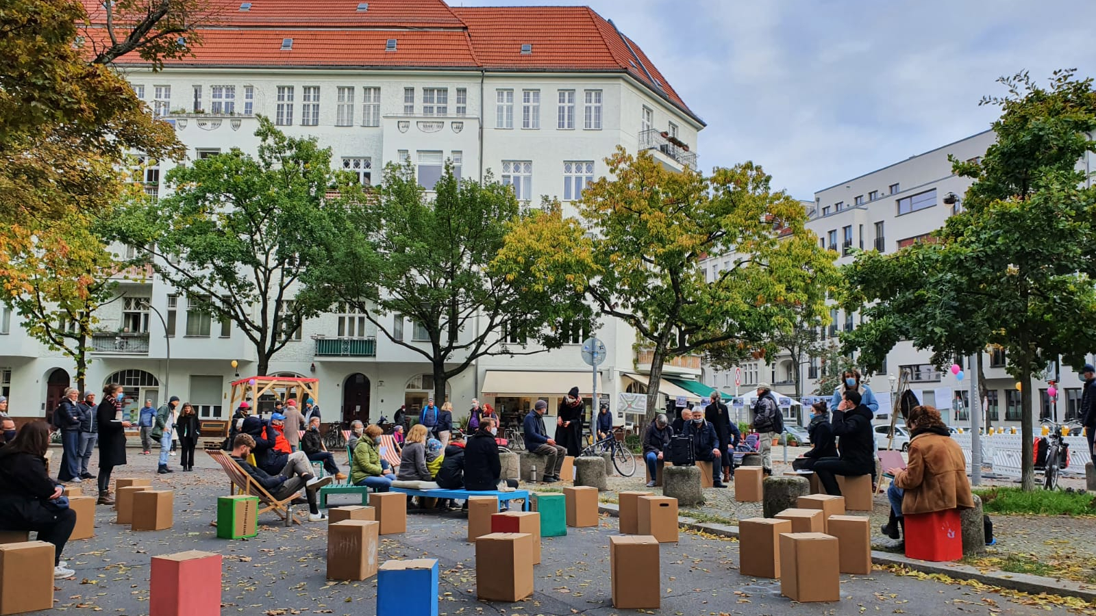 A picture of a town square that has been repurposed. Brightly coloured paper stools have been placed on the street.