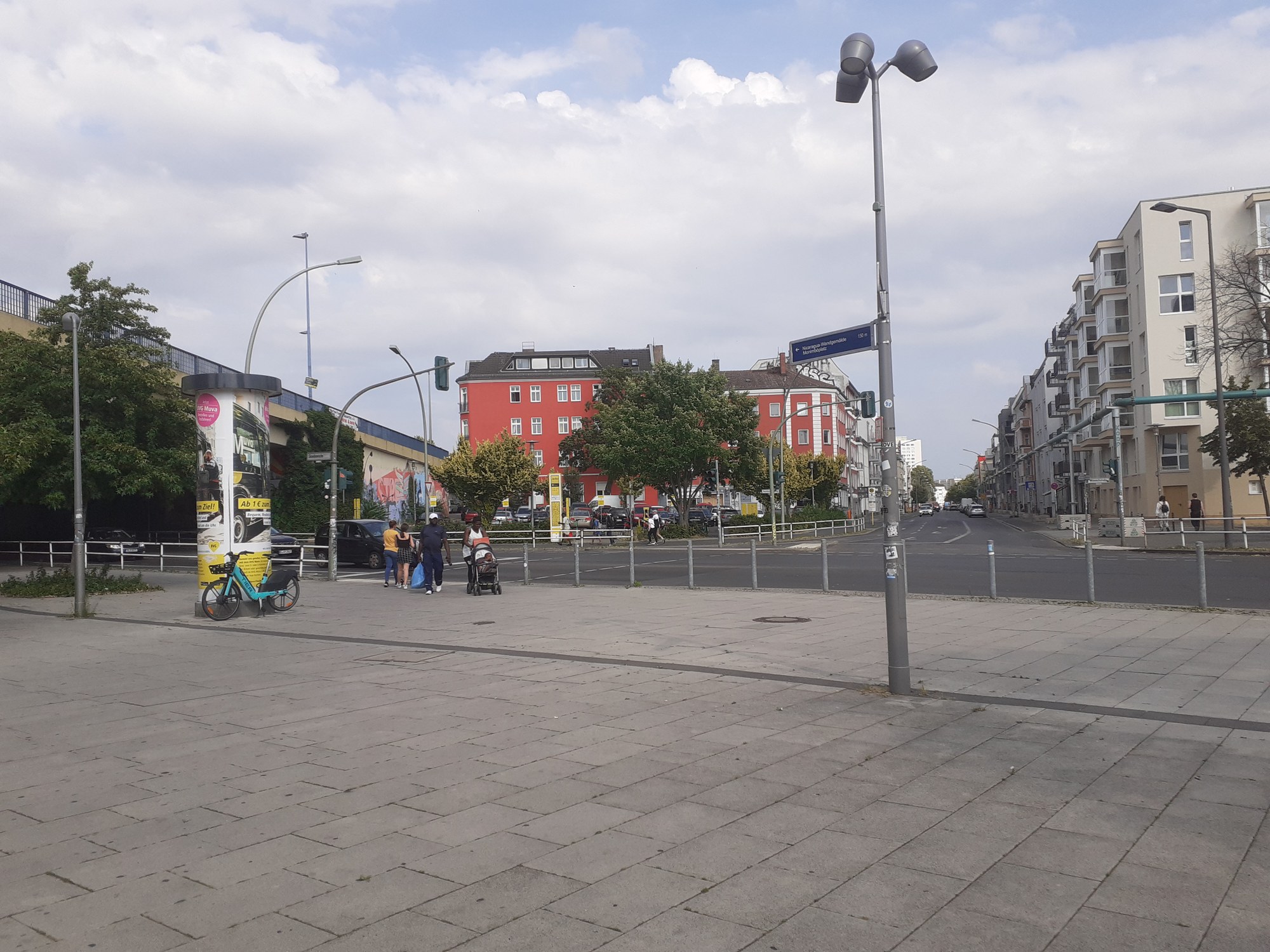A paved station forecourt, where a Jelbi mobility station can be seen behind a road junction.