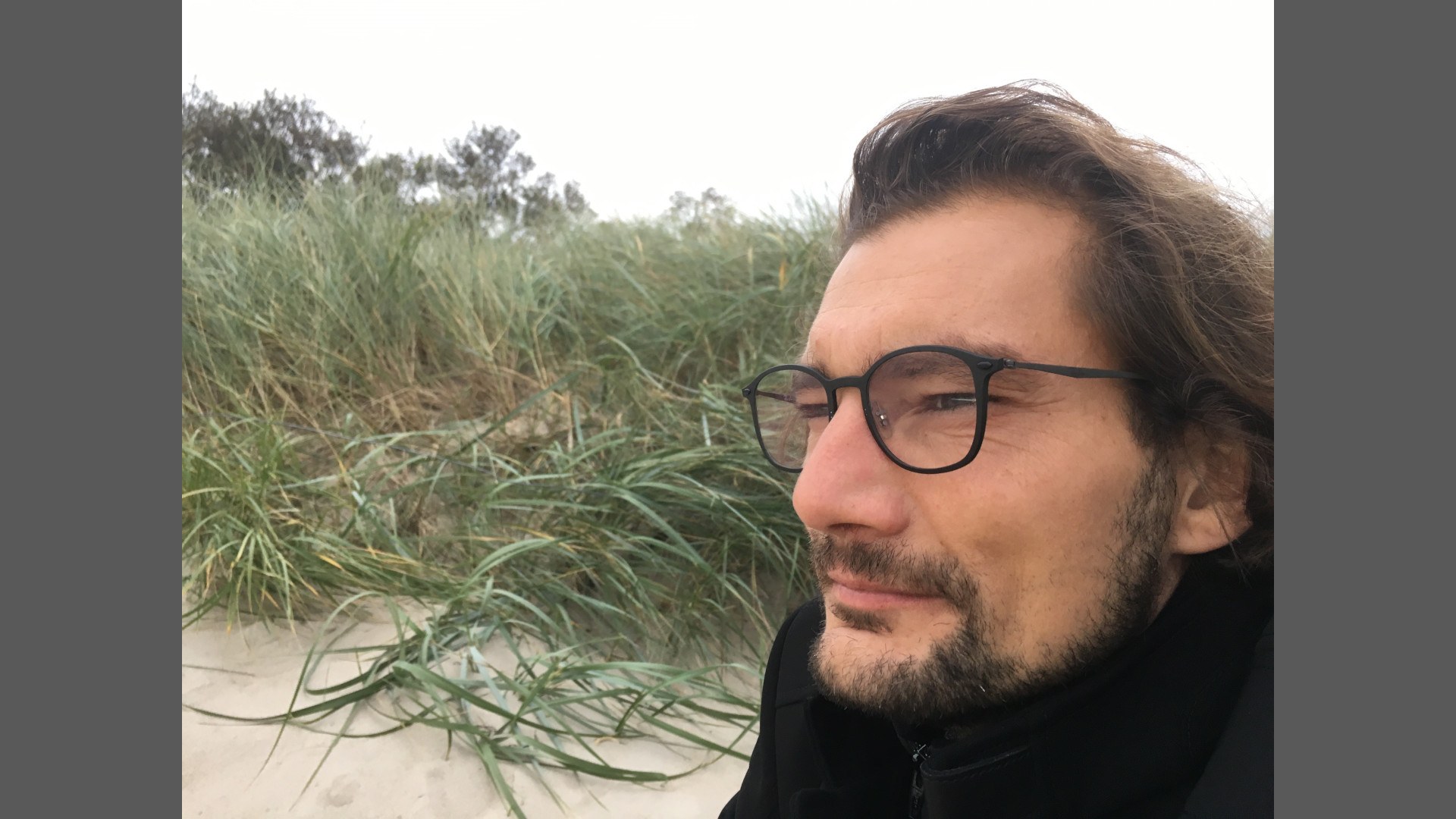 Portrait of Dr Stephan Müller in sand dunes, looking into the distance.
