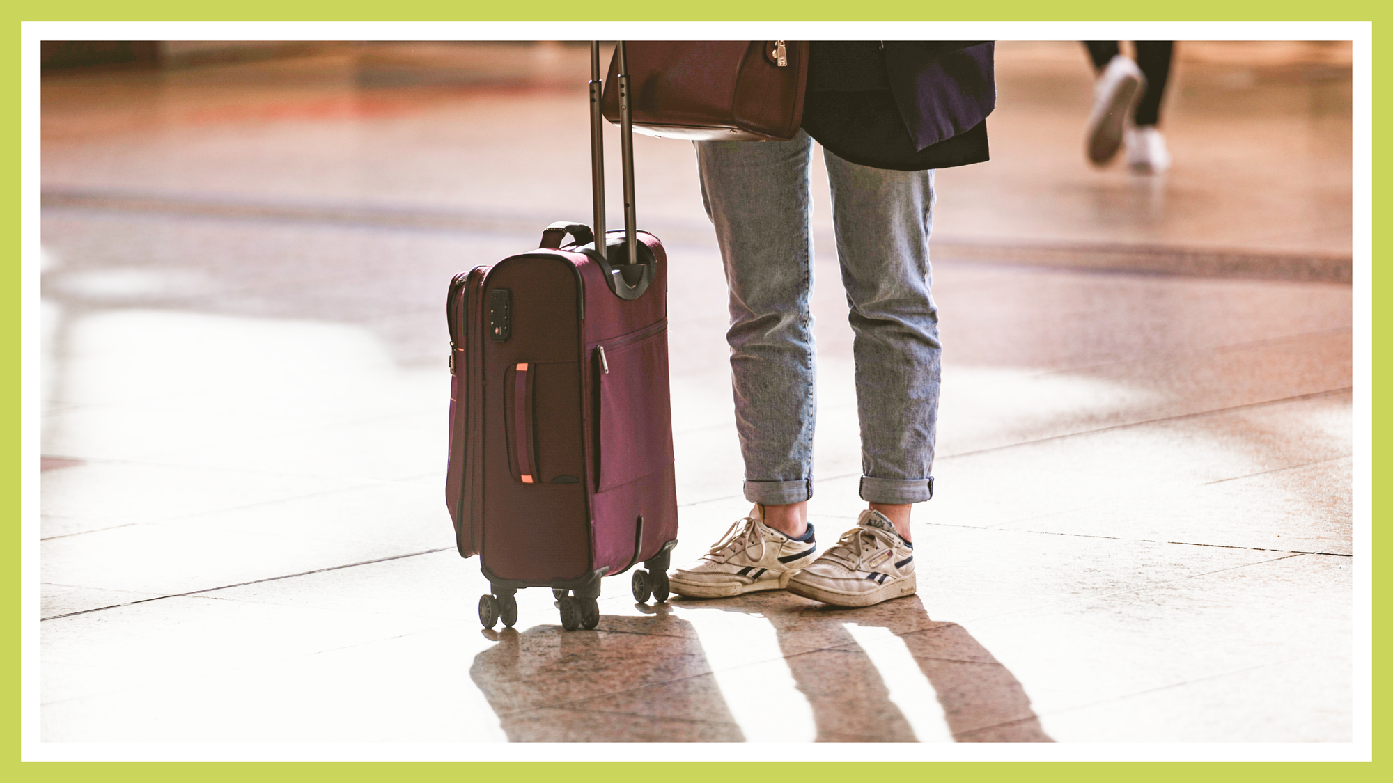 The photo shows a person at a train station, capturing only their lower body. They are pulling a suitcase.
