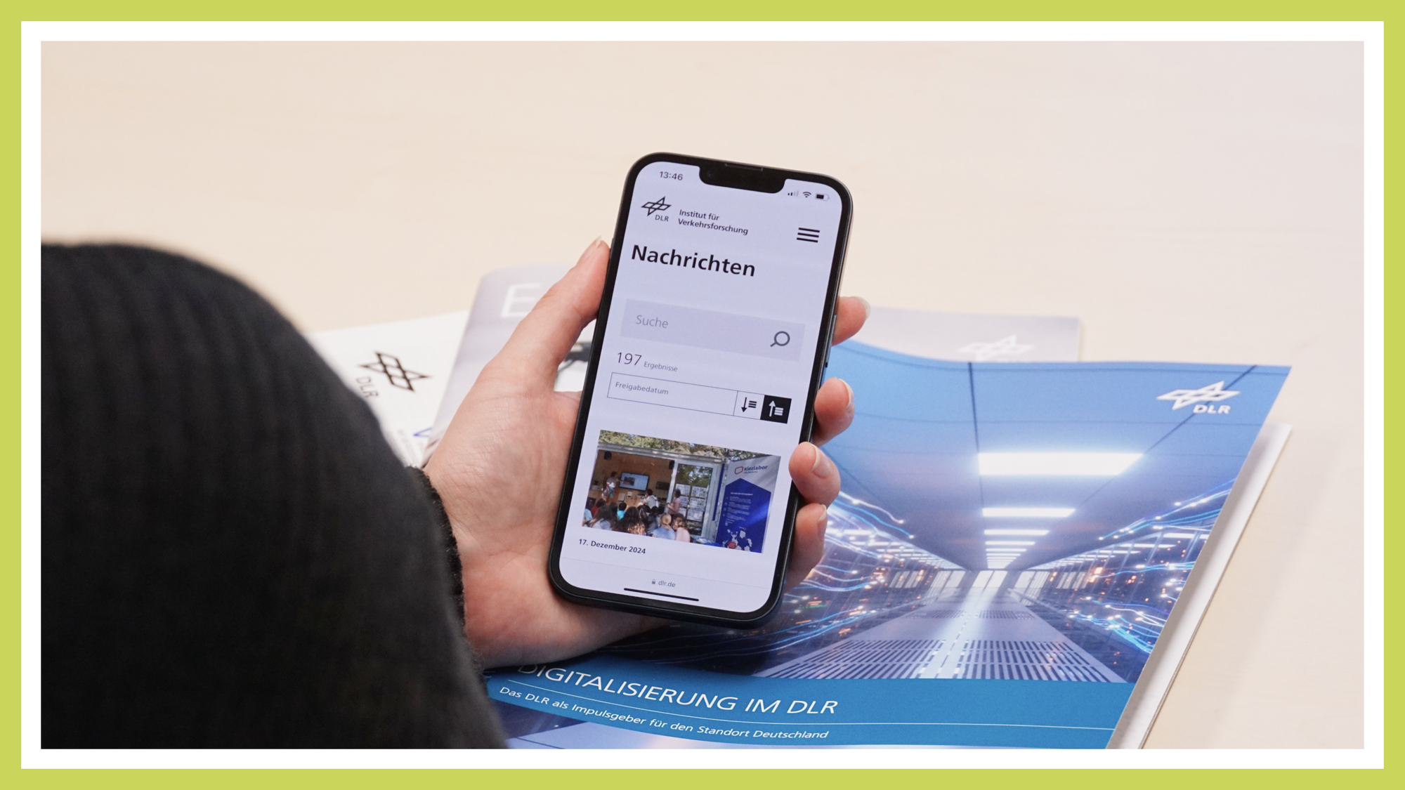 A person holding a smartphone is visible. The smartphone displays the news page of the Institute for Transport Research.